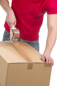 Apartments for rent in Spring TX A man is wrapping a box with tape in his apartment.